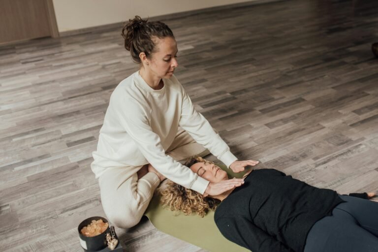 Reikibehandelaar werkt aan de benen van iemand die op een yogamat ligt