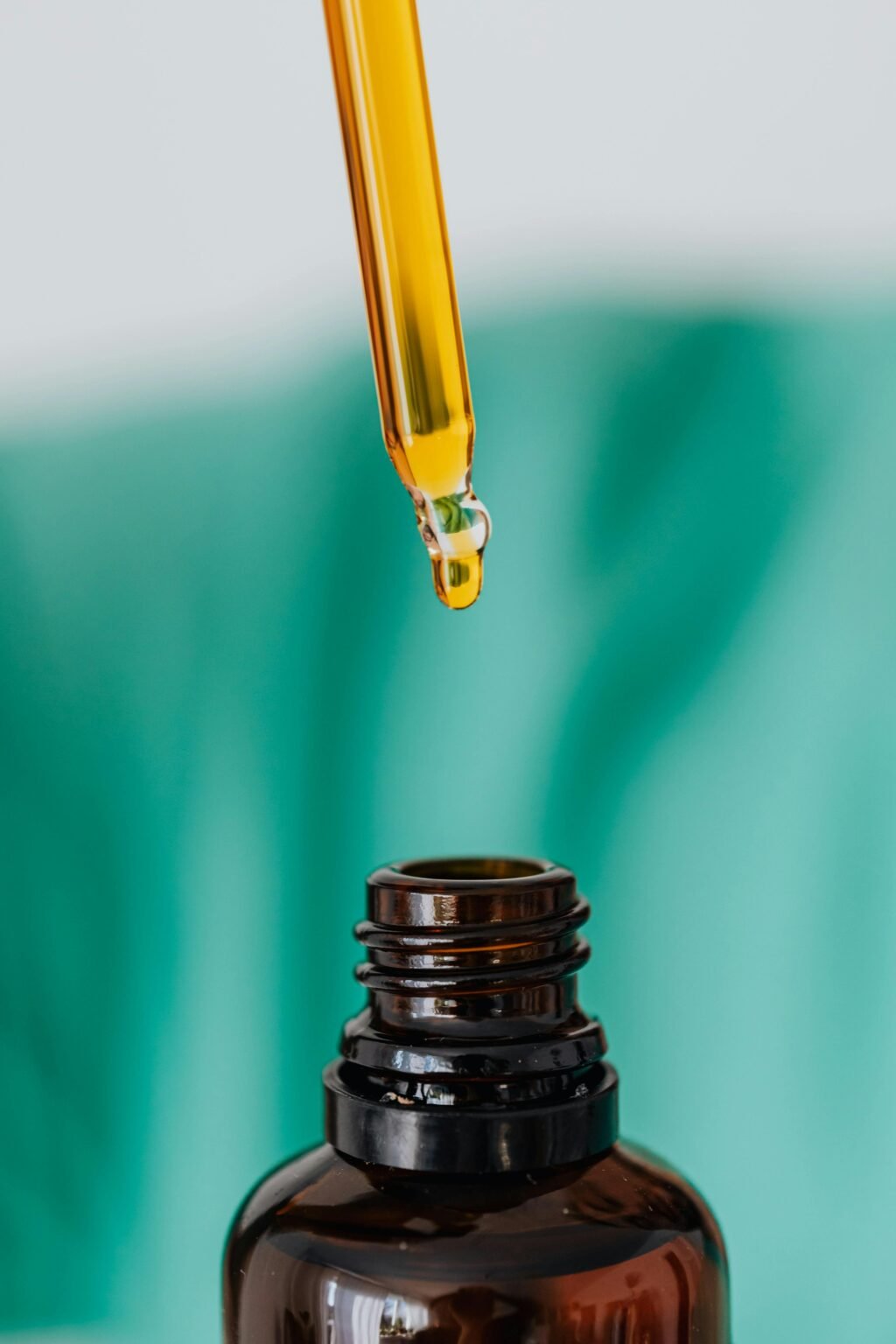 Pipet druppelt bloesemremedie in een bruin flesje tegen een groene achtergrond