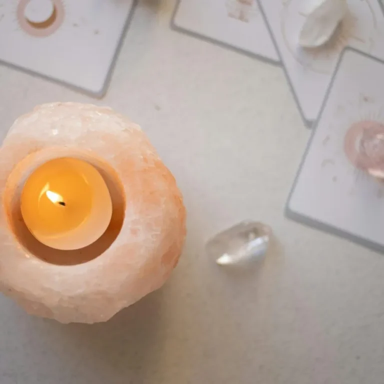 Brandend waxinelichtje in een zoutsteenhouder tussen kaarten en kristallen