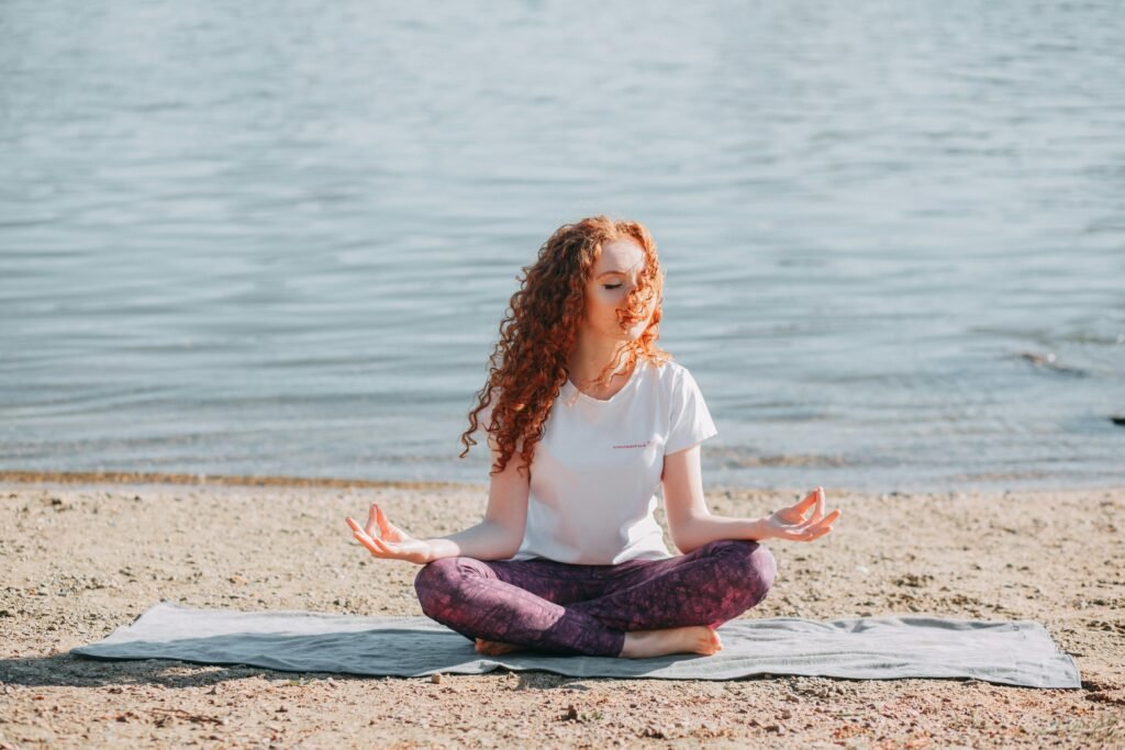 Vrouw mediteert op een yogamat aan het water