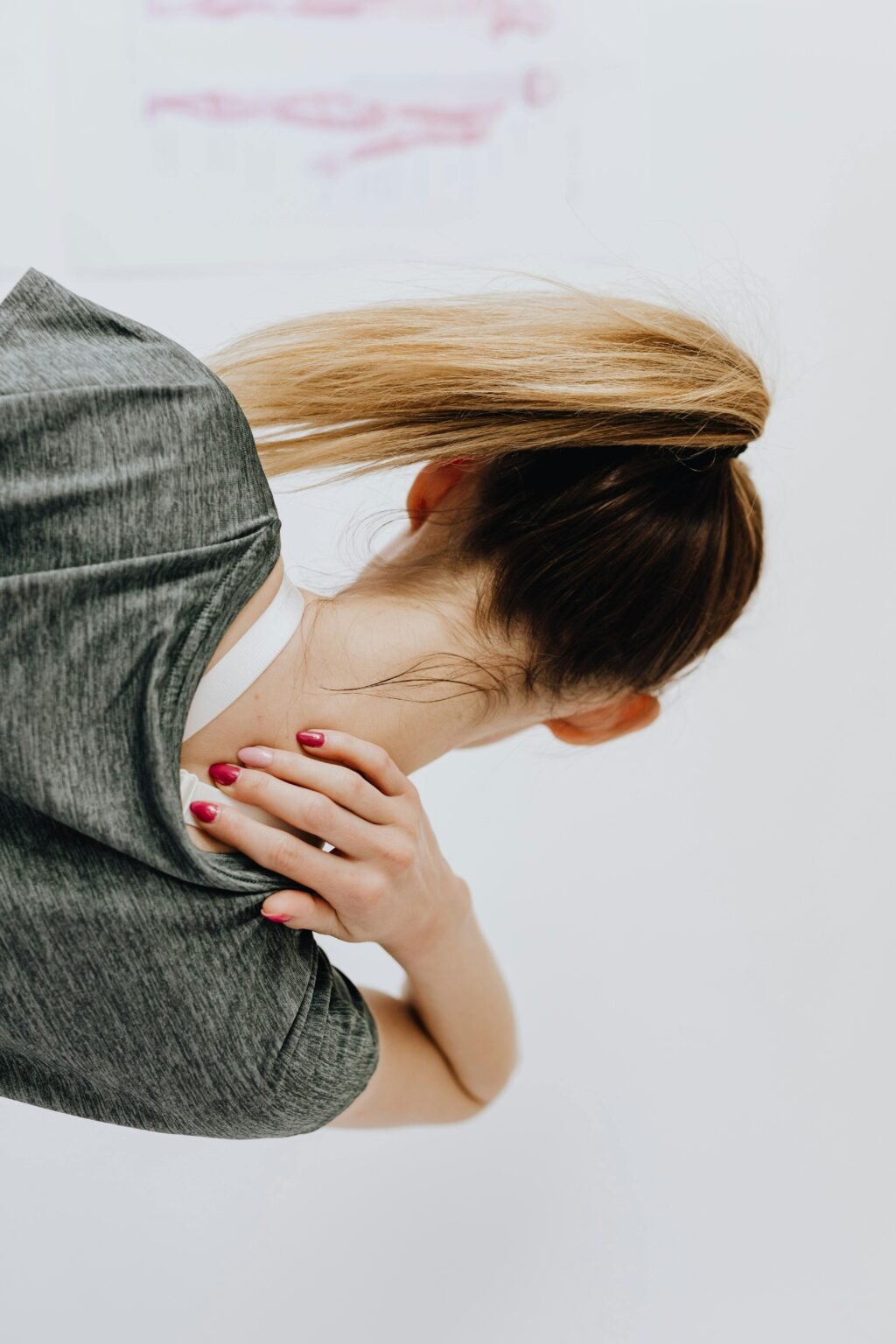 Vrouw buigt voorover en wrijft over haar gespannen nek