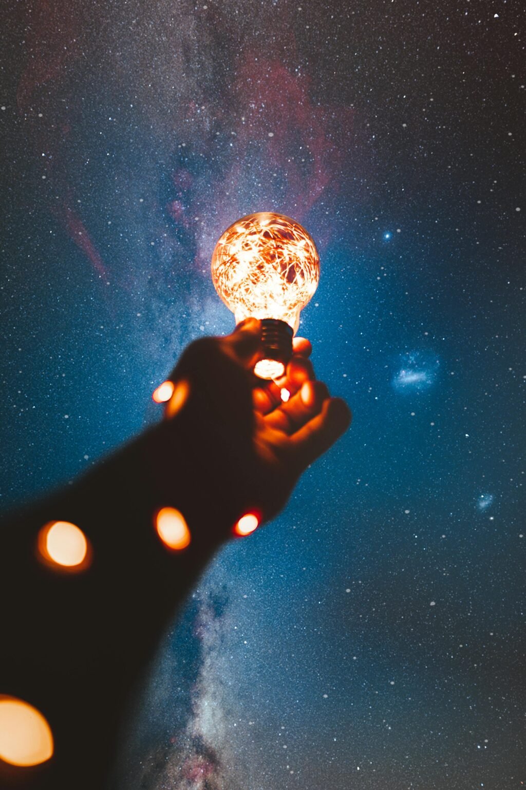 Hand houdt een lichtgevende bol tegen een sterrenhemel