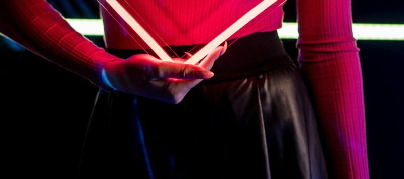 Persoon houdt een lichtgevend neonhart voor de borst