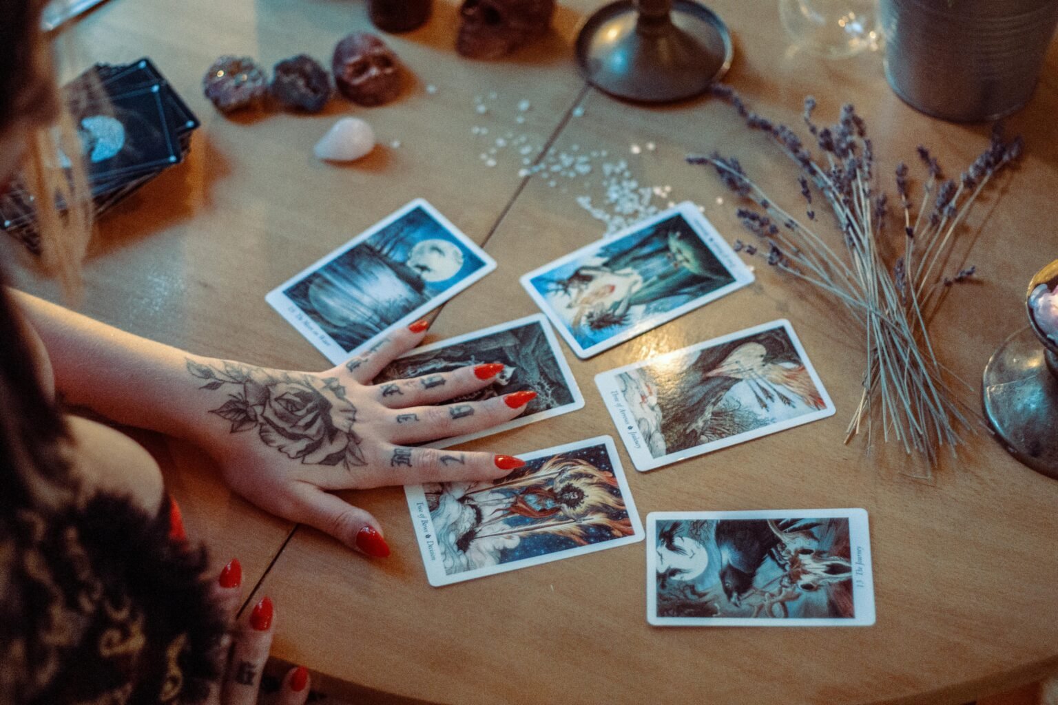 Hand met henna legt tarotkaarten op een houten tafel