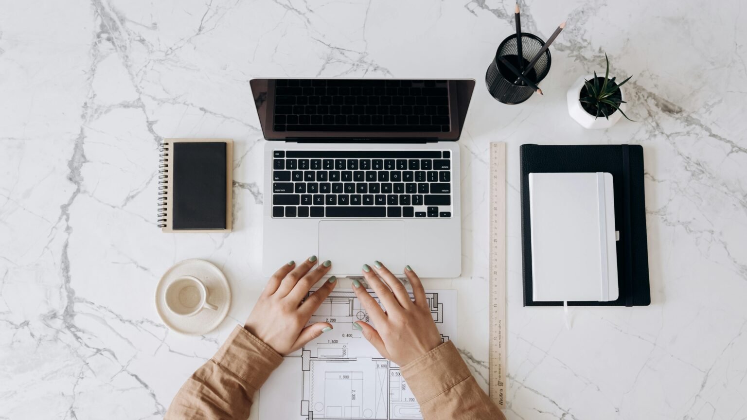 Handen typen op een laptop op een opgeruimd marmeren bureau