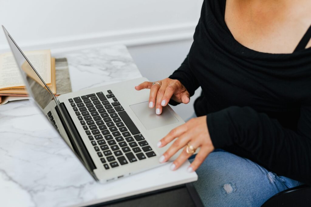 Vrouw werkt op een laptop aan een marmeren tafel