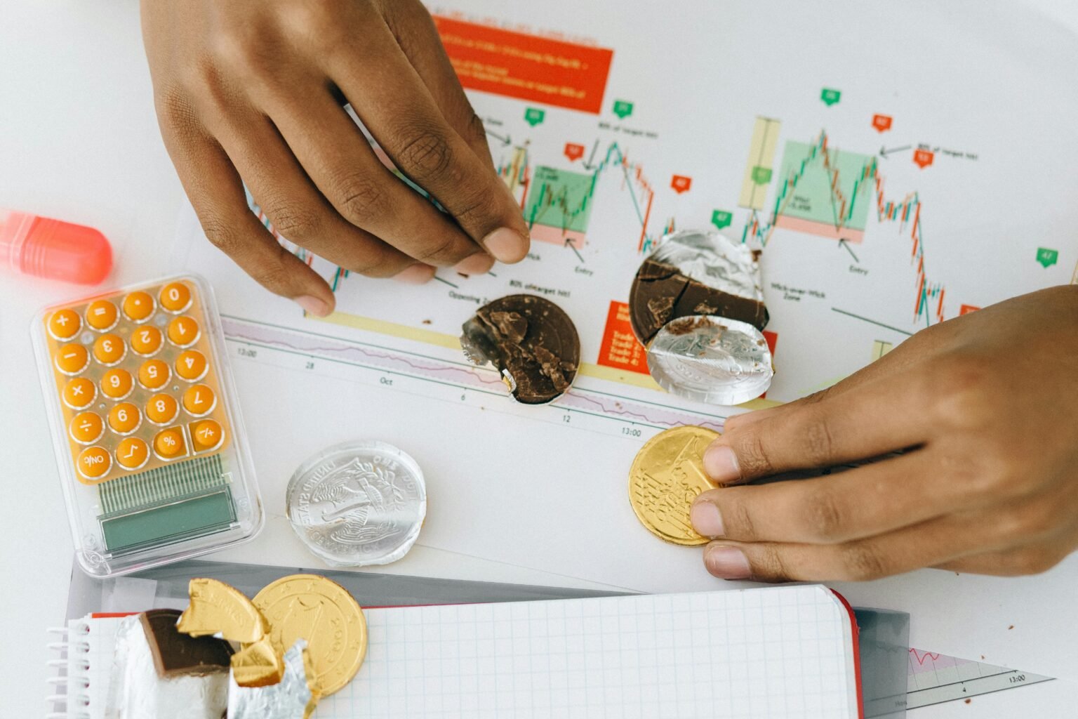 Handen tellen gouden munten boven beursgrafieken