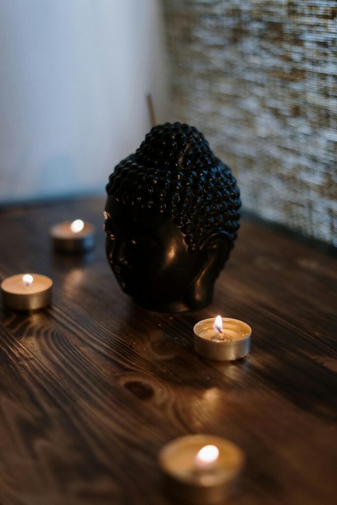 Boeddhabeeldje met brandende theelichtjes op een houten tafel