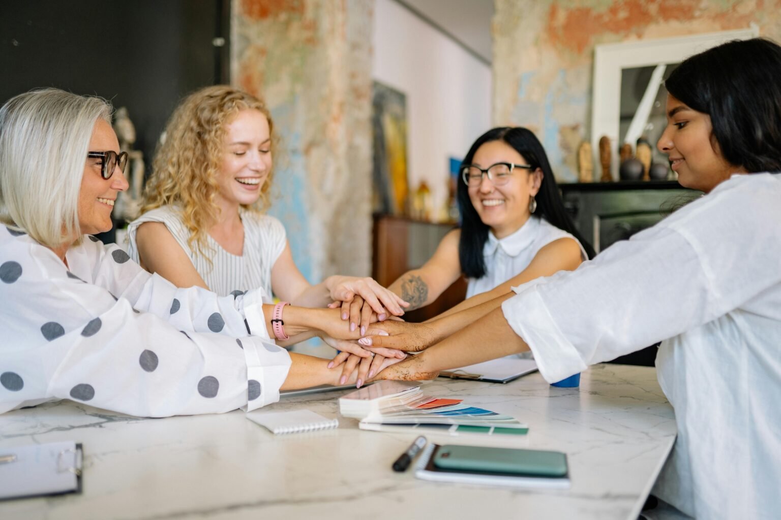 Groep vrouwen legt de handen op elkaar aan tafel
