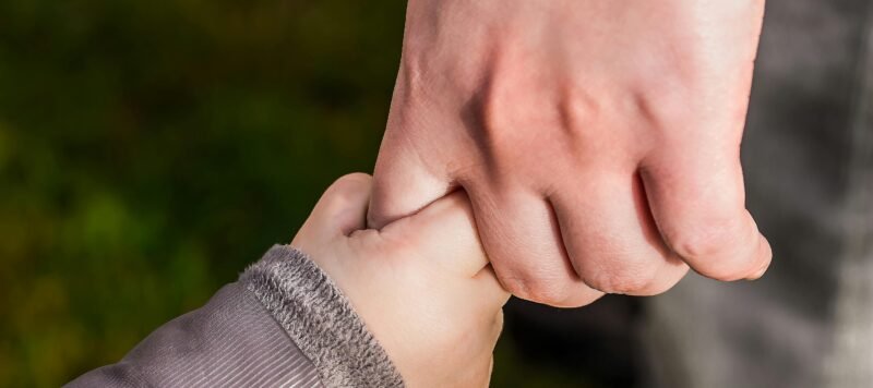 Kinderhandje houdt de hand van een volwassene vast