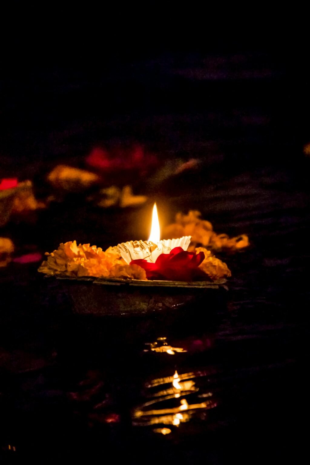 Brandend lichtje met bloemen drijft op donker water