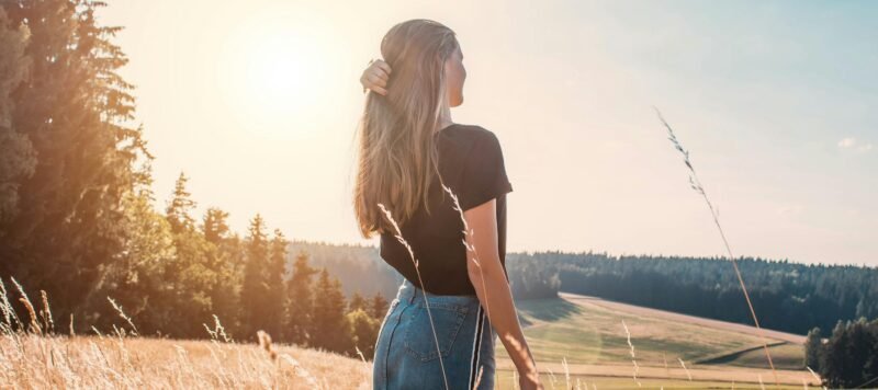 Vrouw loopt van achteren gezien door een zonnig korenveld
