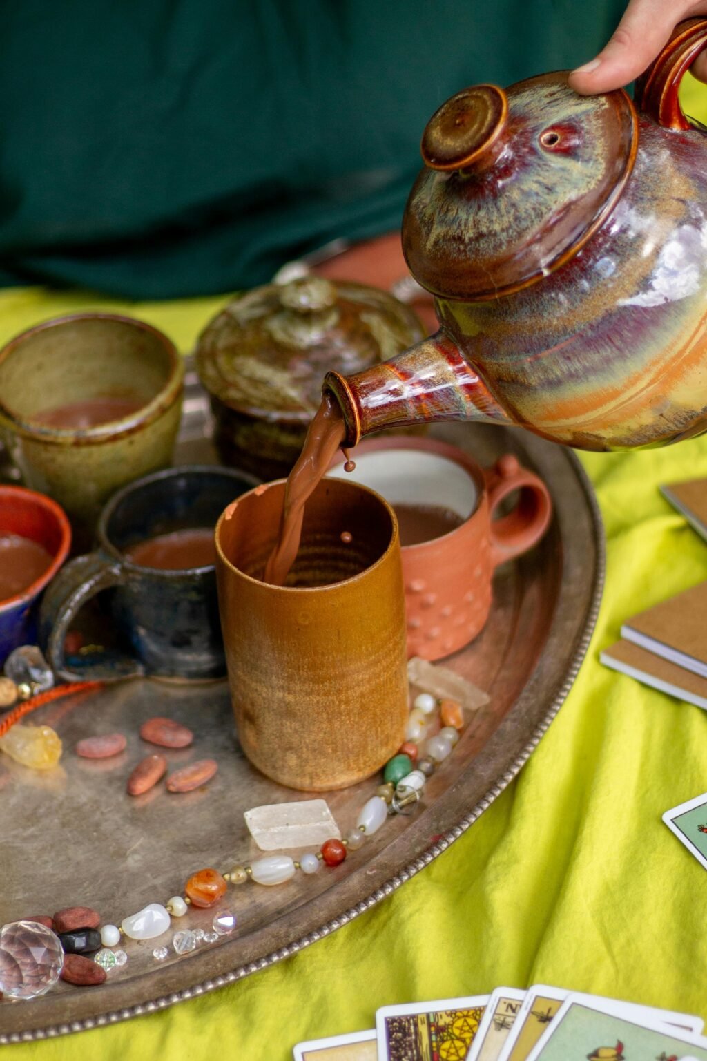 Cacaoceremonie met kannen, kopjes en kaarten op een gele doek