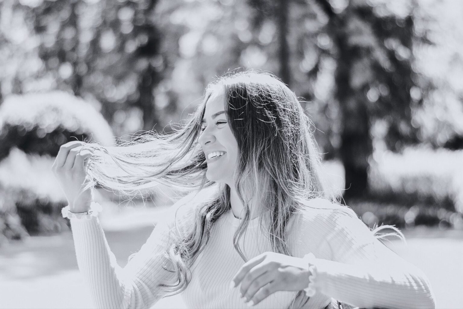 Vrouw lacht met haar haren in de wind tijdens een wandeling buiten