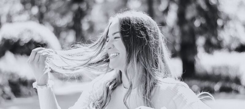 Vrouw lacht met haar haren in de wind tijdens een wandeling buiten