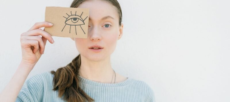 Vrouw houdt een kaart met een getekend oog voor haar gezicht