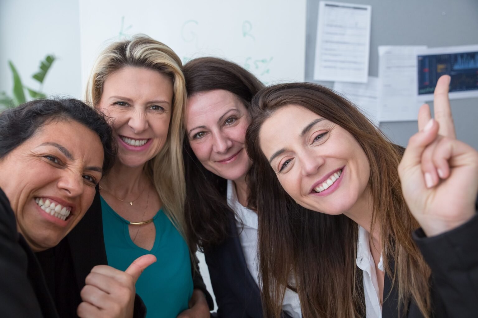 Vier vrouwen staan lachend bij elkaar in een kantoorruimte