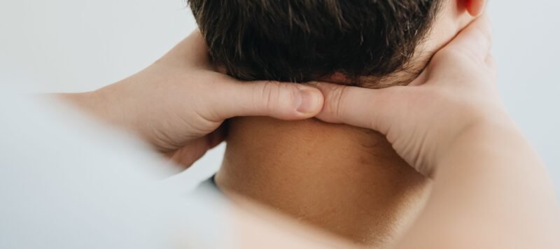 Twee handen rusten in de nek van iemand die met de rug naar de camera zit