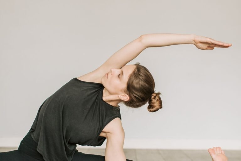 Vrouw maakt een zijwaartse strekking op een yogamat in een lichte studio