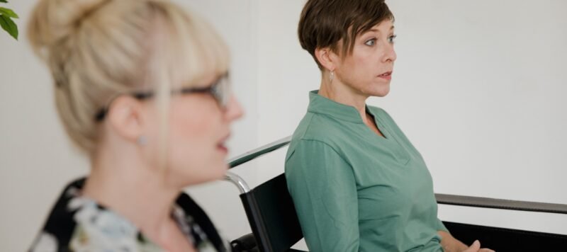 Twee vrouwen zitten tegenover elkaar tijdens een begeleidingsgesprek